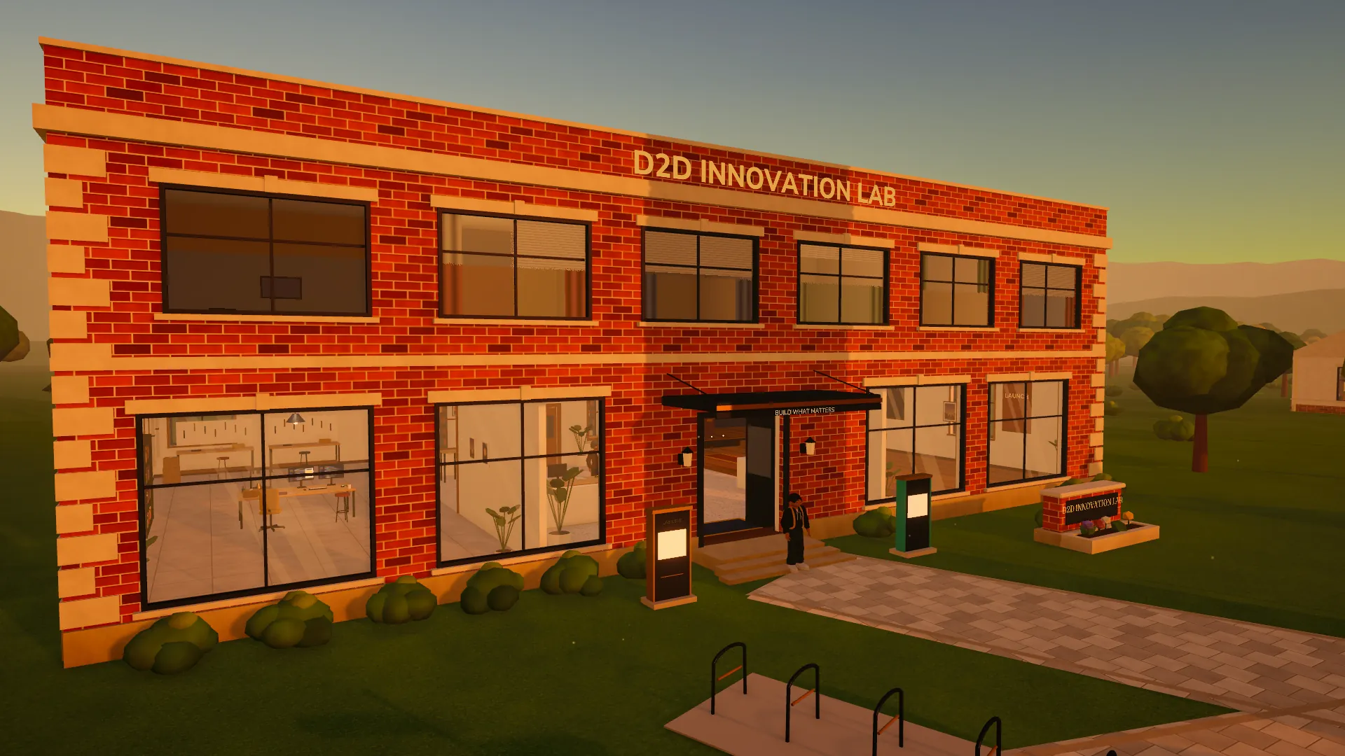 The D2D Innovation Lab at sunset: a red-brick building with tall windows, a sign on the roofline and bike racks out front.