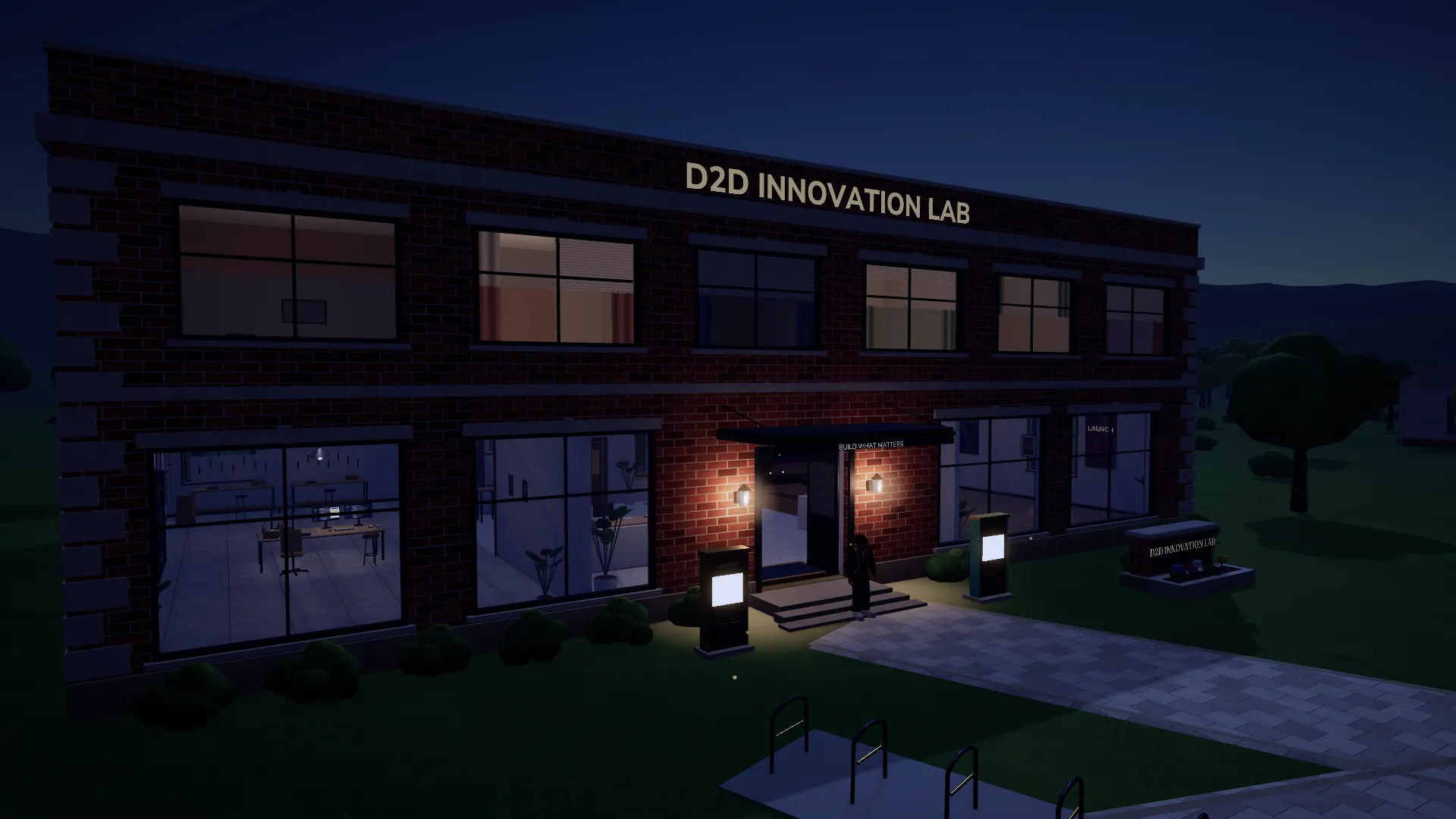 The D2D Innovation Lab at night, its windows and entrance lamps glowing over the plaza.